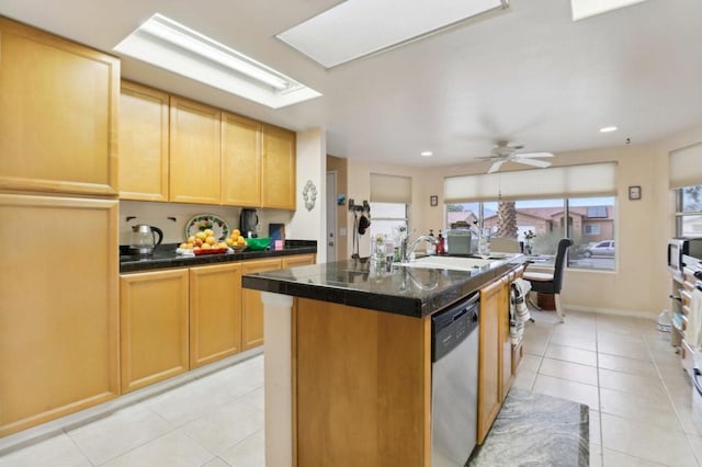 kitchen with sink, ceiling fan, light tile patterned floors, stainless steel dishwasher, and a center island with sink