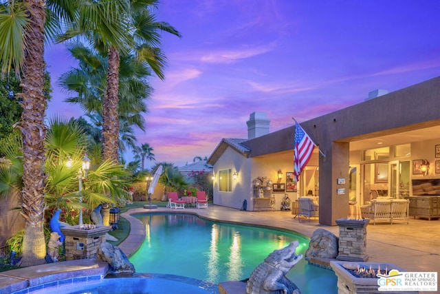 pool at dusk featuring an in ground hot tub and a patio