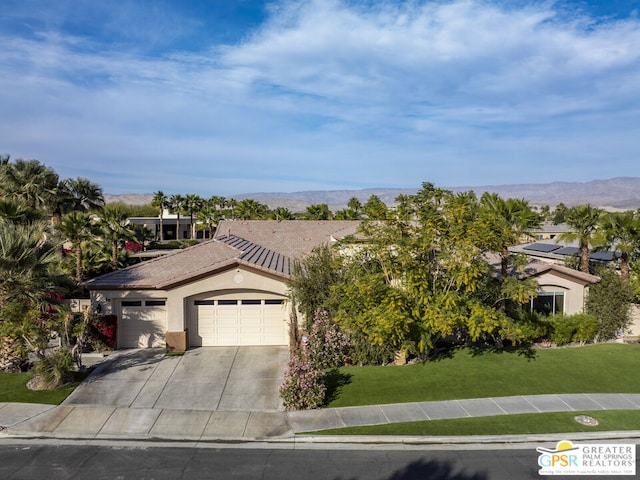 view of front facade featuring a garage, a front lawn, and a mountain view