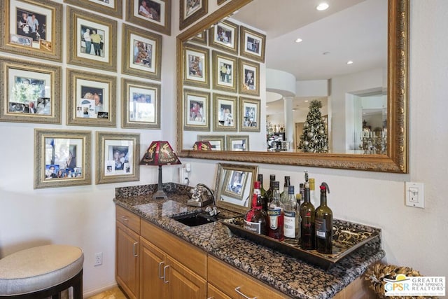 bar featuring dark stone counters and sink