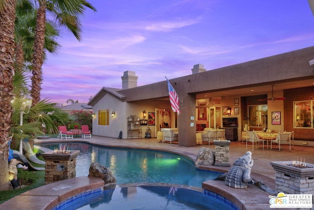 pool at dusk with ceiling fan, an outdoor living space, a patio area, and an in ground hot tub