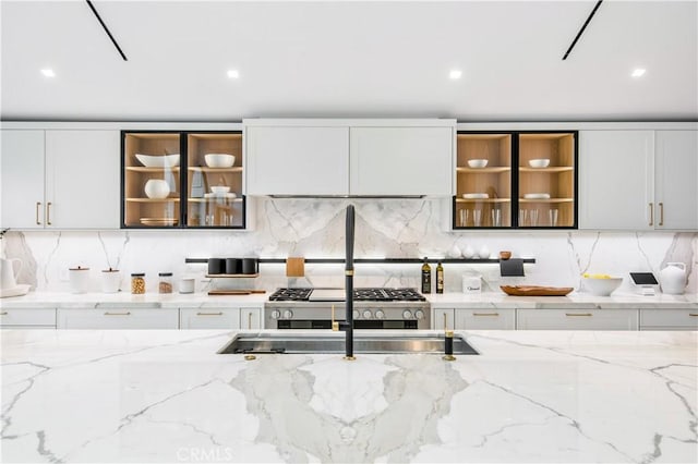 kitchen with tasteful backsplash, sink, light stone counters, and white cabinetry