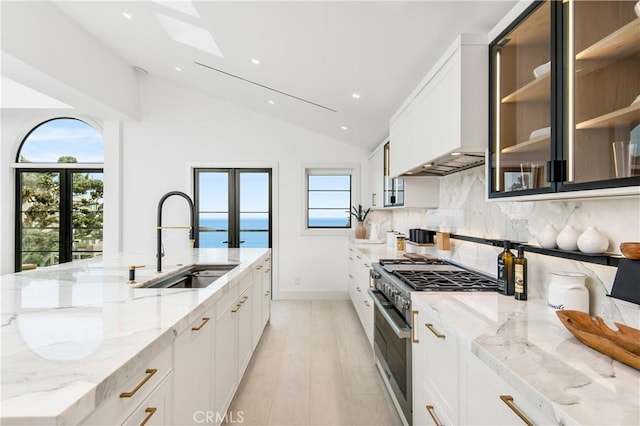 kitchen featuring light stone countertops, sink, white cabinets, and a water view