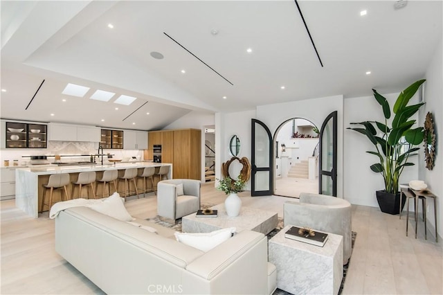 living room featuring light wood-type flooring and lofted ceiling with skylight