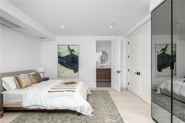 bedroom featuring ensuite bathroom, sink, and light hardwood / wood-style flooring