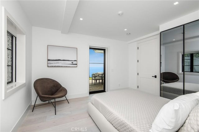 bedroom featuring beamed ceiling and light wood-type flooring