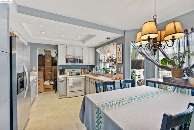 dining space featuring sink, a raised ceiling, and a chandelier