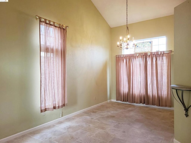 spare room with high vaulted ceiling and an inviting chandelier