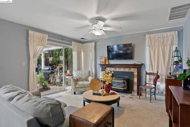 living room featuring a wood stove and ceiling fan