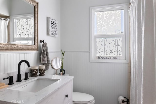 bathroom featuring a wainscoted wall, vanity, and toilet