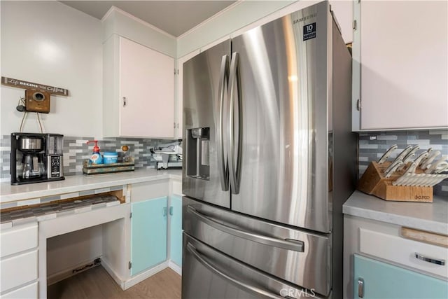 kitchen featuring stainless steel fridge with ice dispenser, decorative backsplash, wood-type flooring, and white cabinets