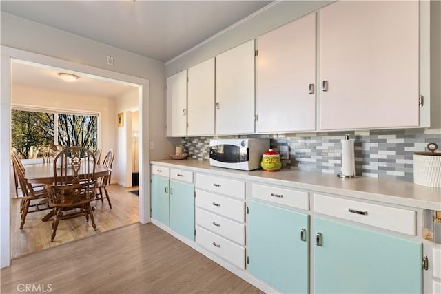 kitchen featuring decorative backsplash, white cabinets, and light wood-type flooring