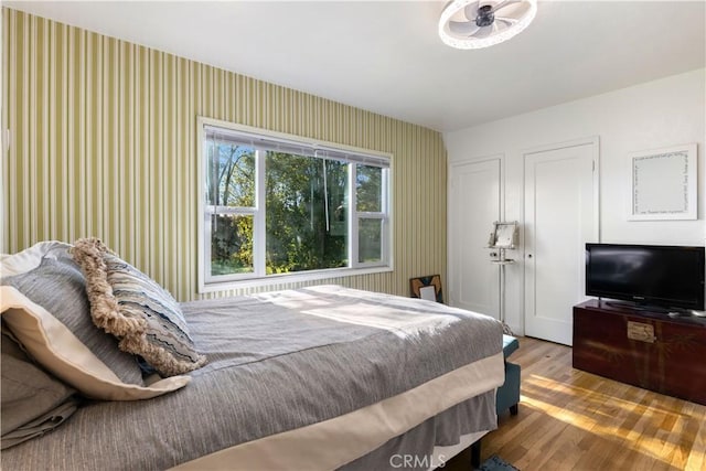 bedroom with wood finished floors and wallpapered walls