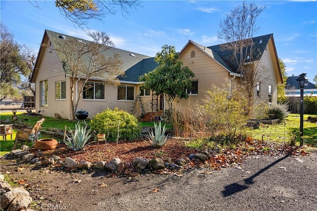 view of front of house with a shingled roof and stucco siding