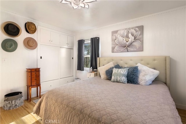 bedroom with ornamental molding and light hardwood / wood-style floors