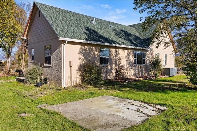 rear view of house with a patio, a shingled roof, a lawn, and cooling unit