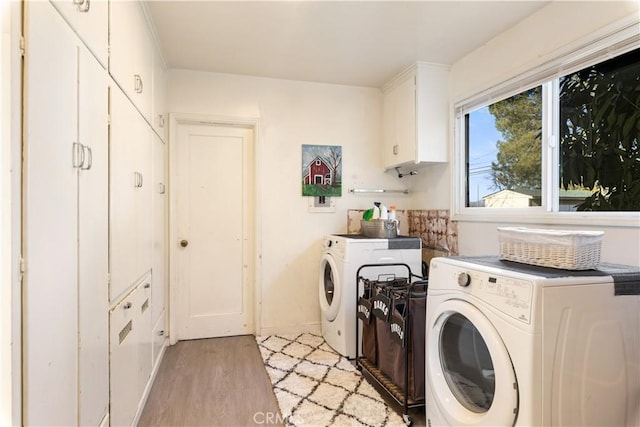 washroom with cabinets, washer and dryer, and light wood-type flooring