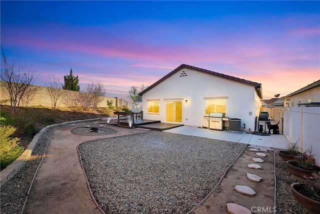 back house at dusk featuring central AC unit and a patio area