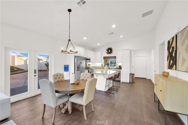 dining space with dark hardwood / wood-style floors, a chandelier, and high vaulted ceiling