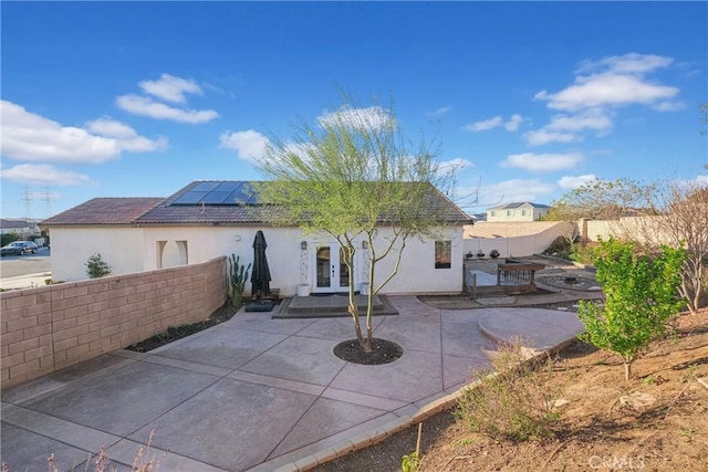 rear view of property featuring a patio area, french doors, and solar panels