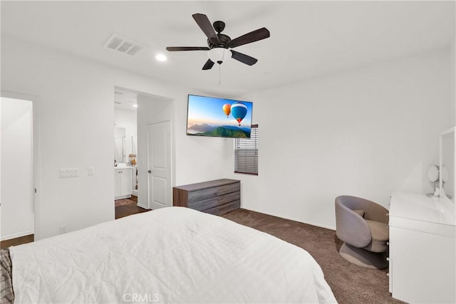 bedroom with ensuite bath, ceiling fan, and dark colored carpet