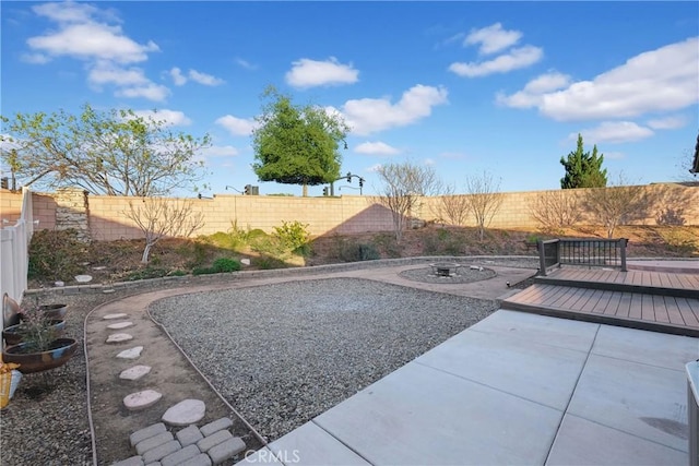 view of yard featuring a wooden deck, a fire pit, and a patio area