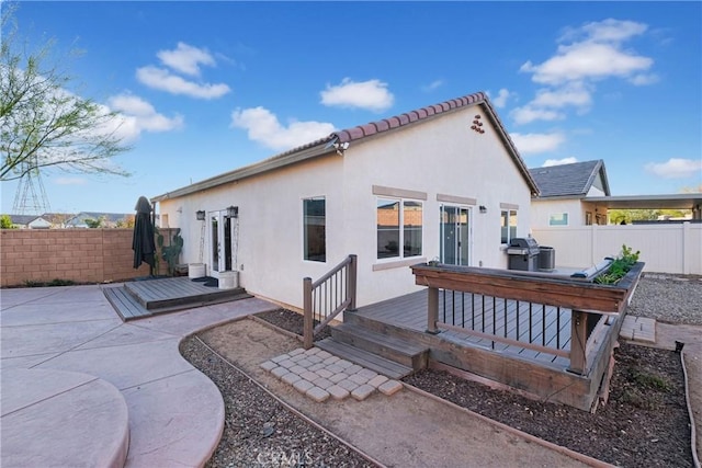 rear view of property featuring a wooden deck and a patio area