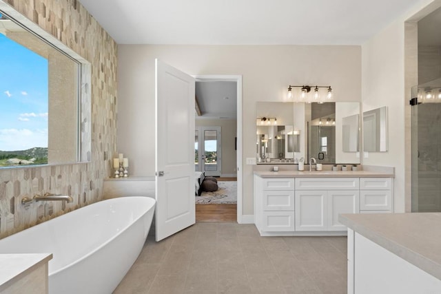 bathroom with a wealth of natural light, a bathtub, vanity, and tile patterned flooring