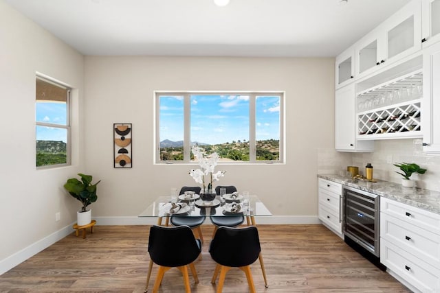 dining space with wood-type flooring, bar area, and wine cooler