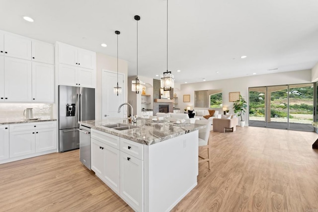 kitchen with an island with sink, appliances with stainless steel finishes, sink, and white cabinetry