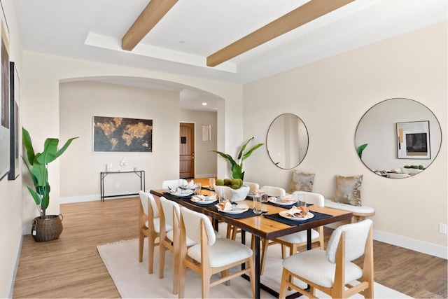 dining area with beamed ceiling and light wood-type flooring