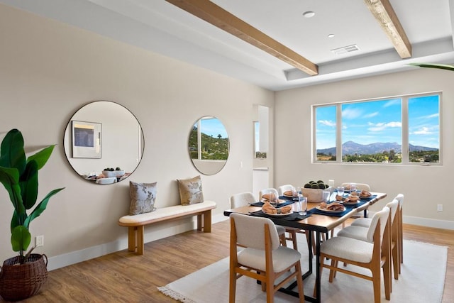 dining space featuring light wood-type flooring, beam ceiling, and a mountain view