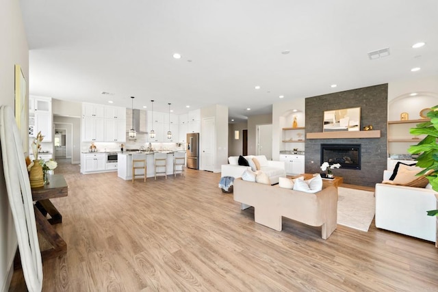 living room with light hardwood / wood-style floors and a large fireplace