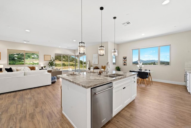 kitchen with white cabinetry, a center island with sink, dishwasher, light stone counters, and sink