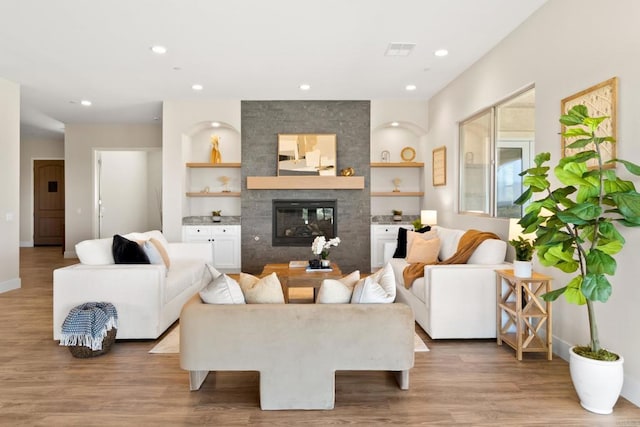 living room with built in features, a large fireplace, and hardwood / wood-style floors