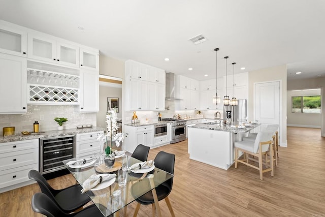 dining area with wine cooler, sink, and light hardwood / wood-style flooring