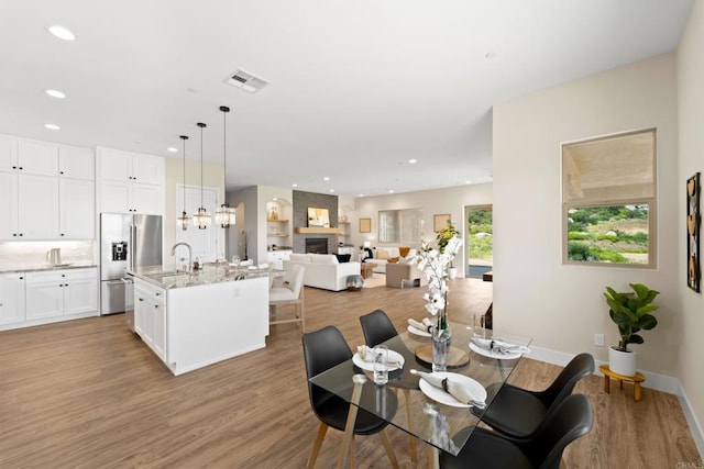 dining area featuring a fireplace, light hardwood / wood-style floors, and sink