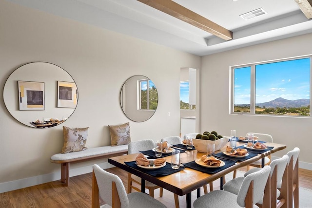 dining room featuring light wood-type flooring, beam ceiling, and a mountain view