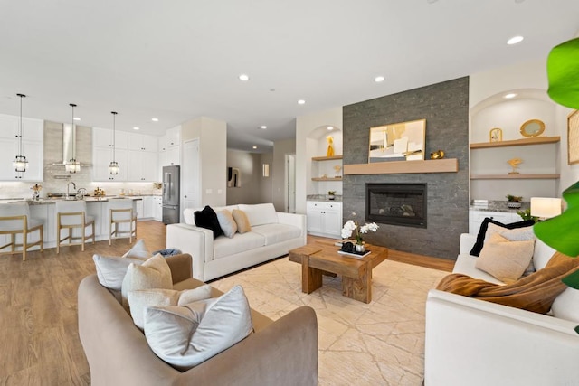 living room with sink, built in shelves, a tile fireplace, and light wood-type flooring