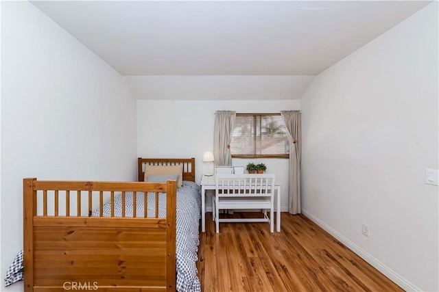 unfurnished bedroom featuring vaulted ceiling and wood-type flooring