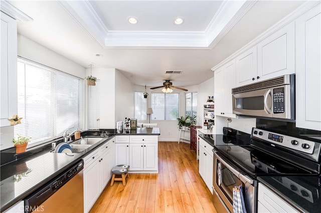 kitchen featuring appliances with stainless steel finishes, white cabinetry, sink, kitchen peninsula, and a raised ceiling