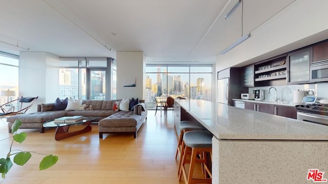 kitchen featuring light stone countertops, a center island, sink, light wood-type flooring, and expansive windows