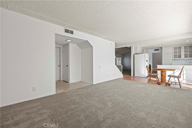 unfurnished living room featuring light carpet and a textured ceiling