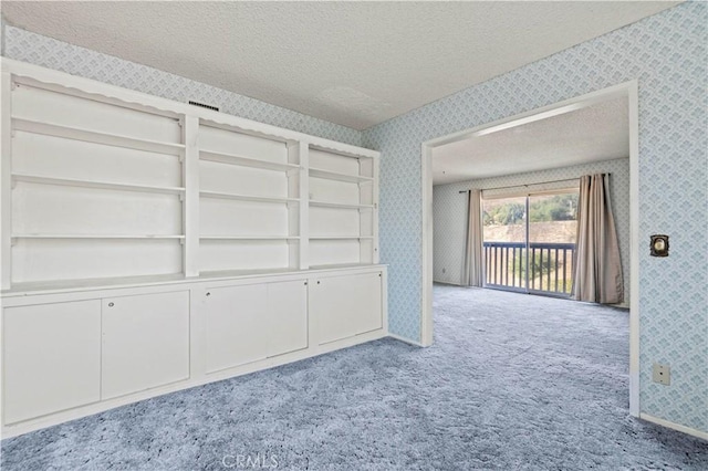 empty room featuring a textured ceiling and light carpet