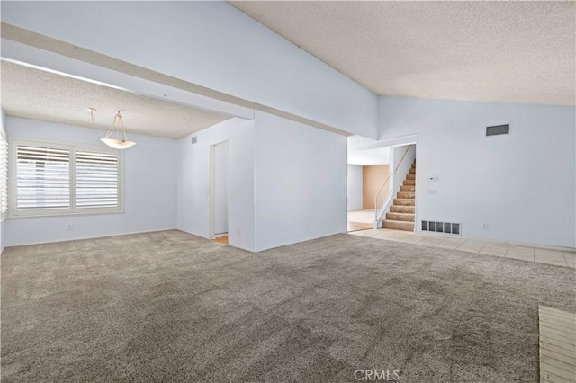 unfurnished living room with light colored carpet, vaulted ceiling, and a textured ceiling