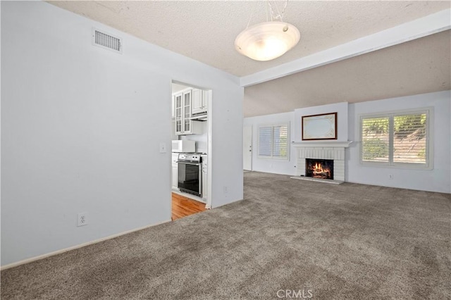 unfurnished living room featuring a textured ceiling, light carpet, vaulted ceiling with beams, and a fireplace