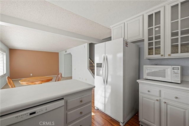 kitchen with hardwood / wood-style flooring, white appliances, white cabinets, and a textured ceiling