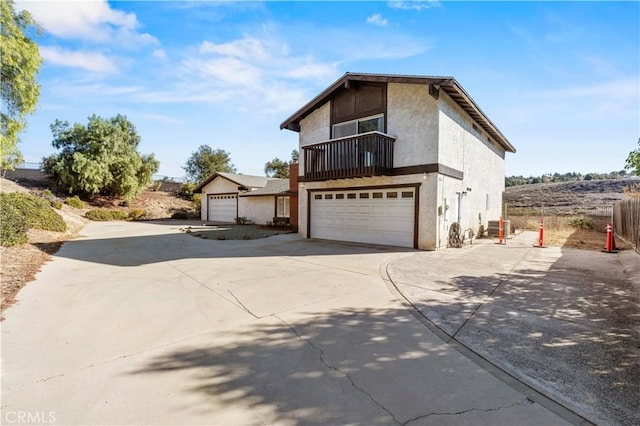 front facade featuring a balcony, cooling unit, and a garage