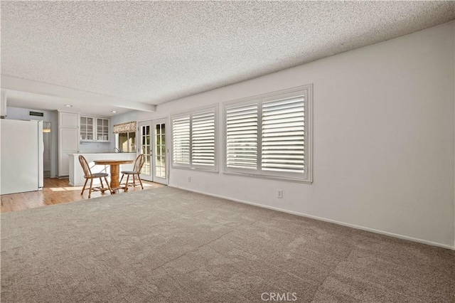 empty room featuring a textured ceiling and light colored carpet