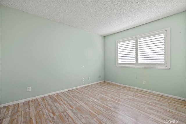 unfurnished room featuring a textured ceiling and light hardwood / wood-style floors